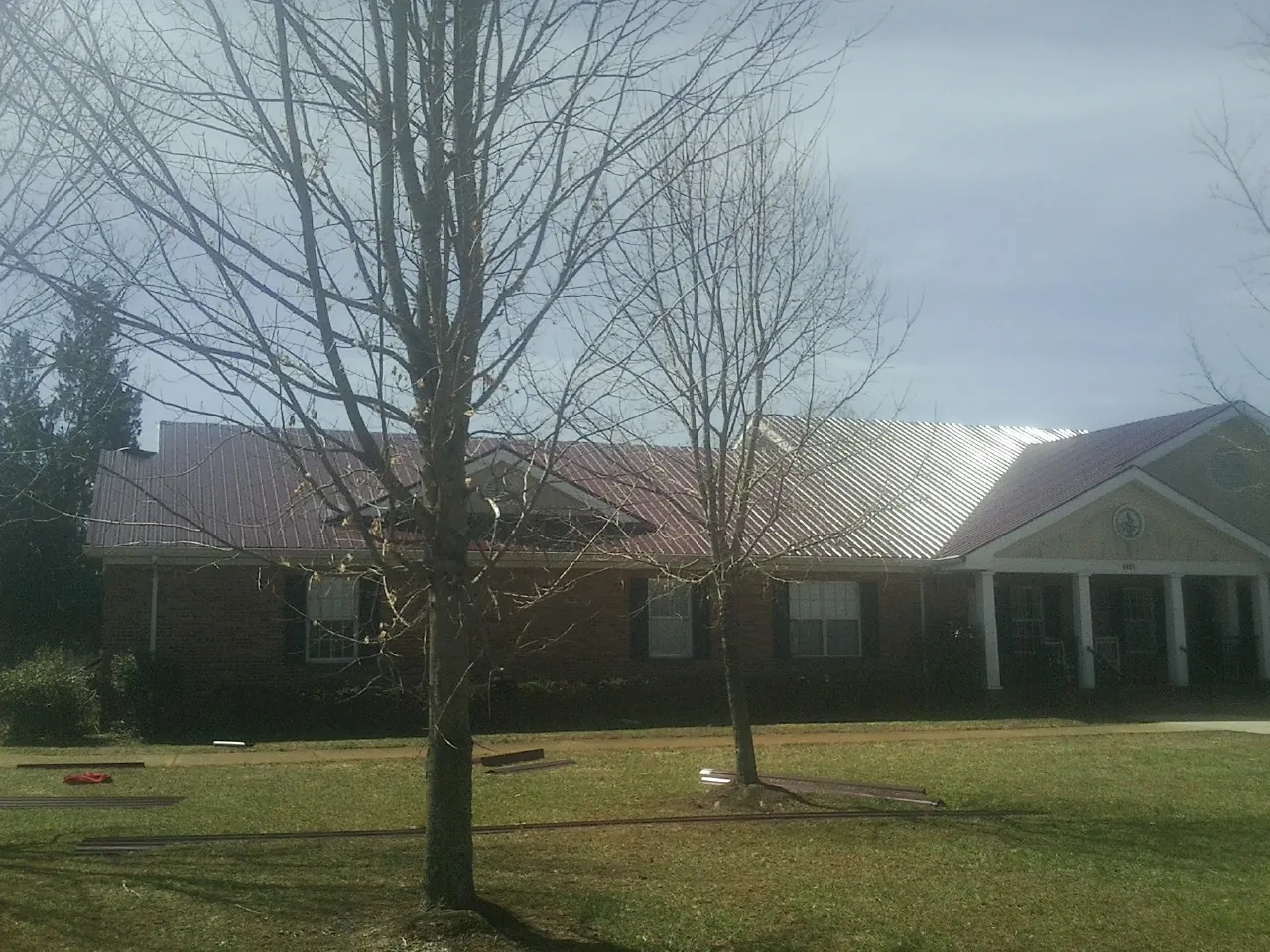 Red metal roof on a brick building seen from the front lawn in Laceyville