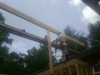 Carpenter setting a ridge beam over a new addition frame — Ice Dam Removal by Roofing Brothers in Laceyville