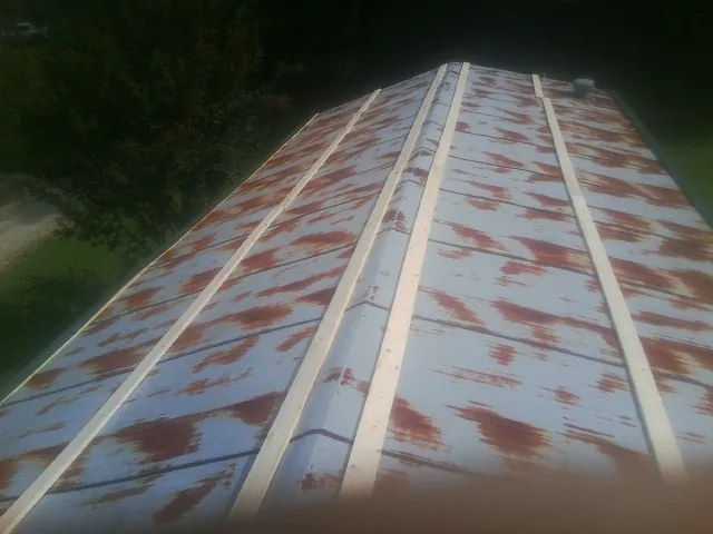 Rusted metal roof panels with new wood purlins before replacement — Storm Damage Roof Repair in Laceyville by Roofing Brothers