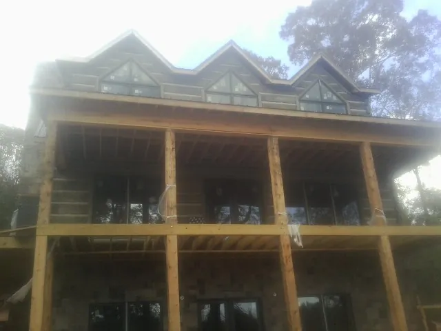 Dormers and porch framing on a large log home under construction — Roof Coating work by our crew in Laceyville