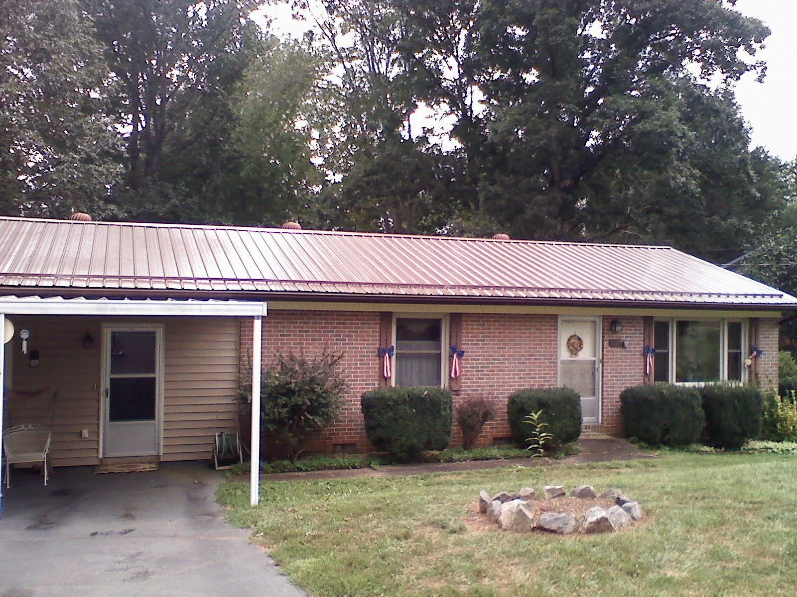 Bronze metal roof and carport on a brick ranch home — Roof Repair work by our crew in Laceyville
