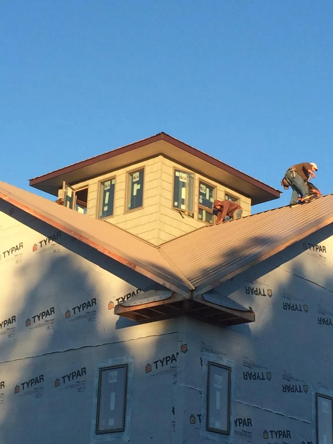 Roofers working around a rooftop cupola on a new metal roof at sunset — Roof Waterproofing in Laceyville by Roofing Brothers